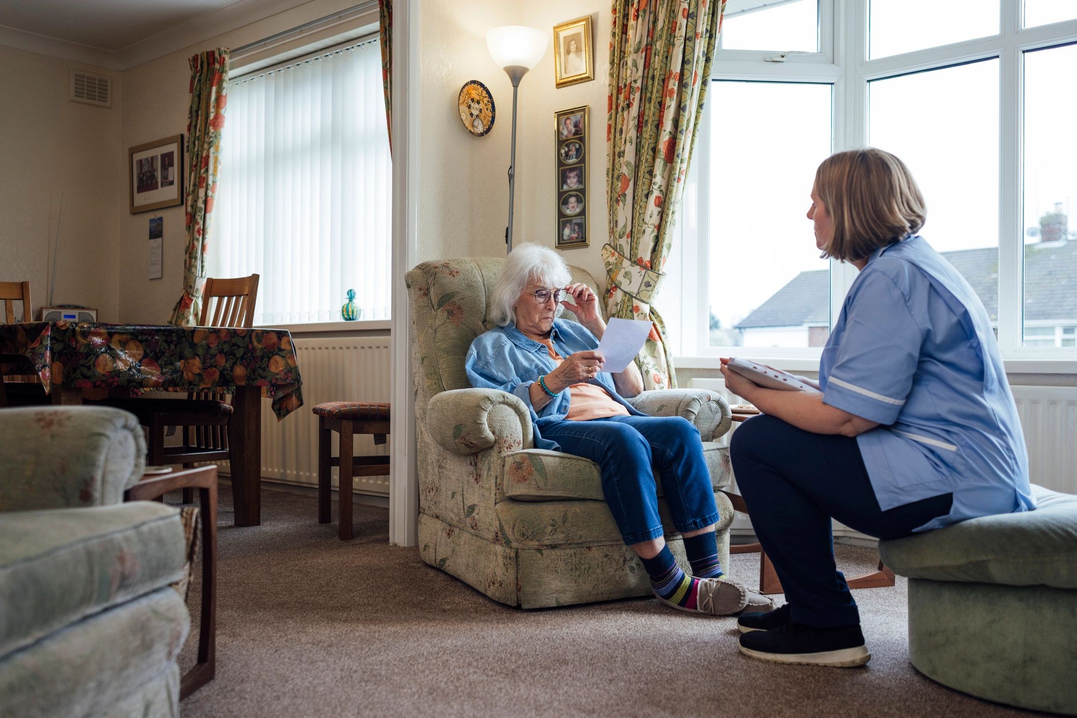 Caregiver speaking with senior woman in a living room
