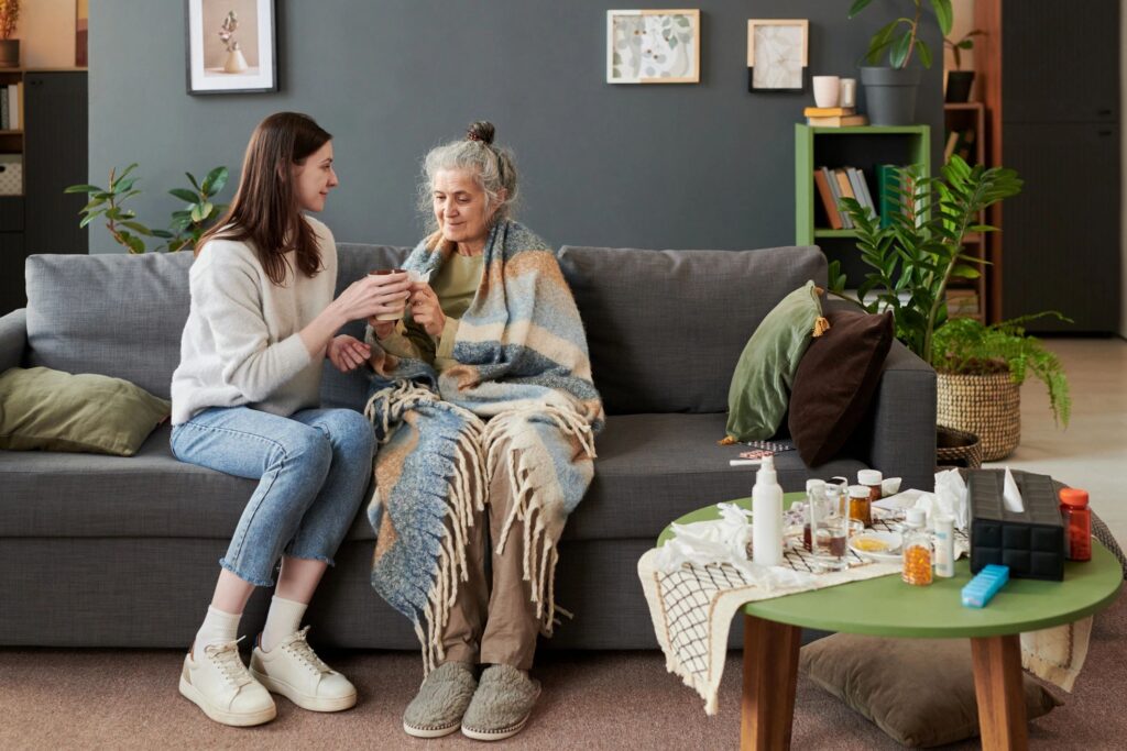 Adult Woman Supporting Senior Mother with Warm Drink during Recovery